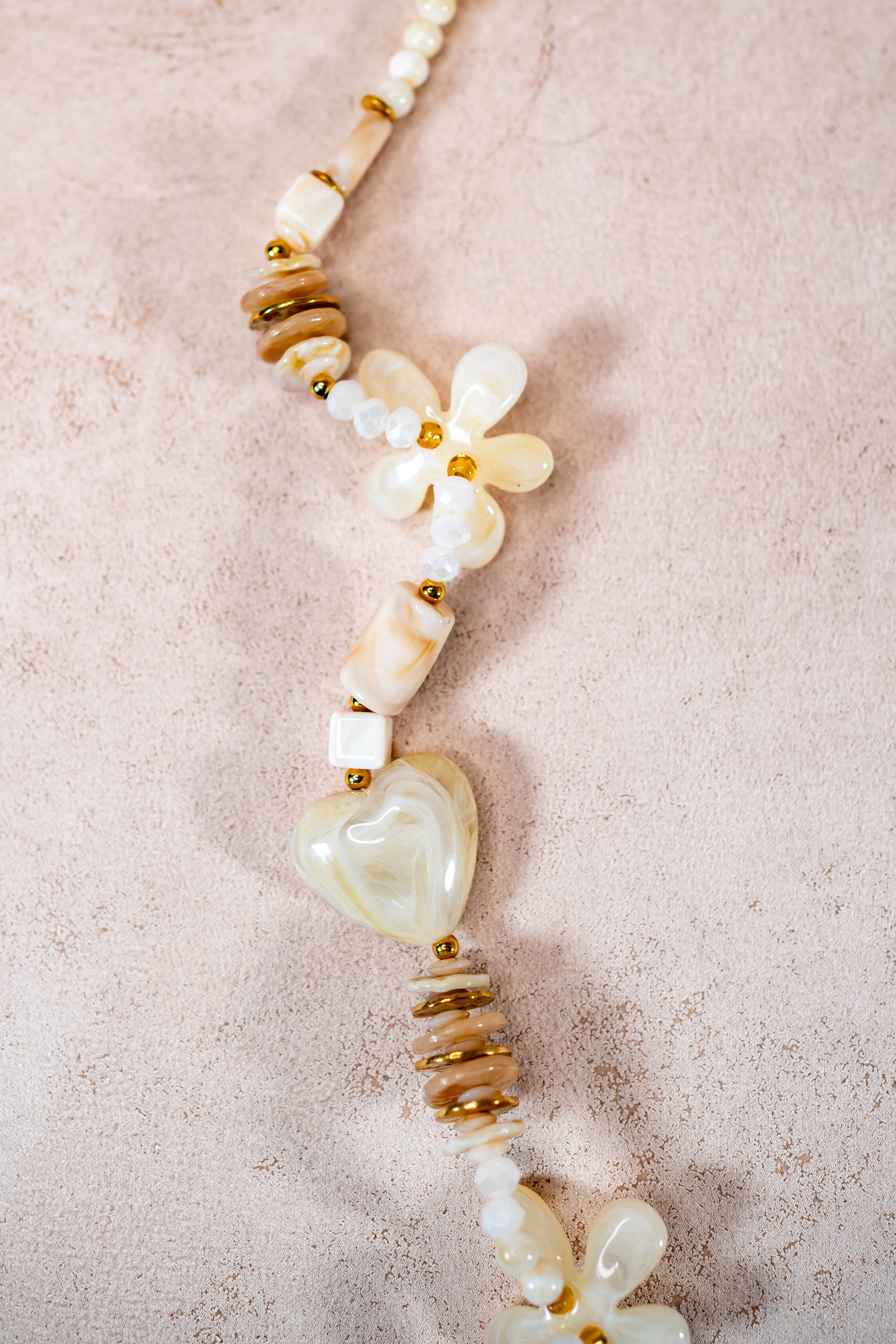 Lange Halskette in Creme mit Herz- und Blütenanhängern