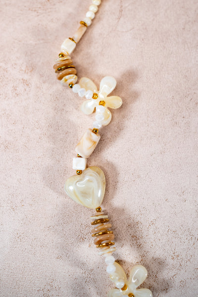 Lange Halskette in Creme mit Herz- und Blütenanhängern